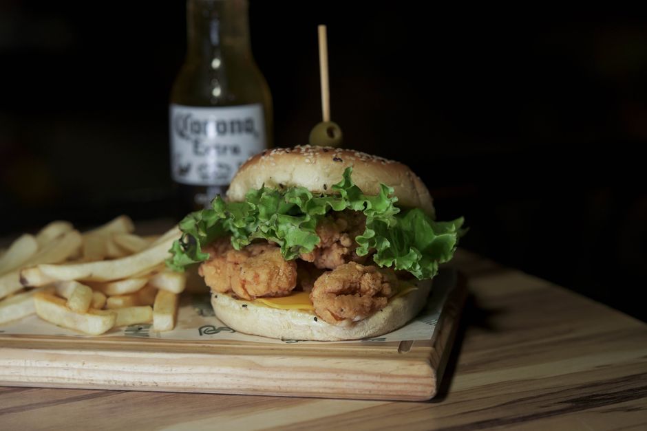 Krosser Chicken-Burger mit Salat auf Holzbrett