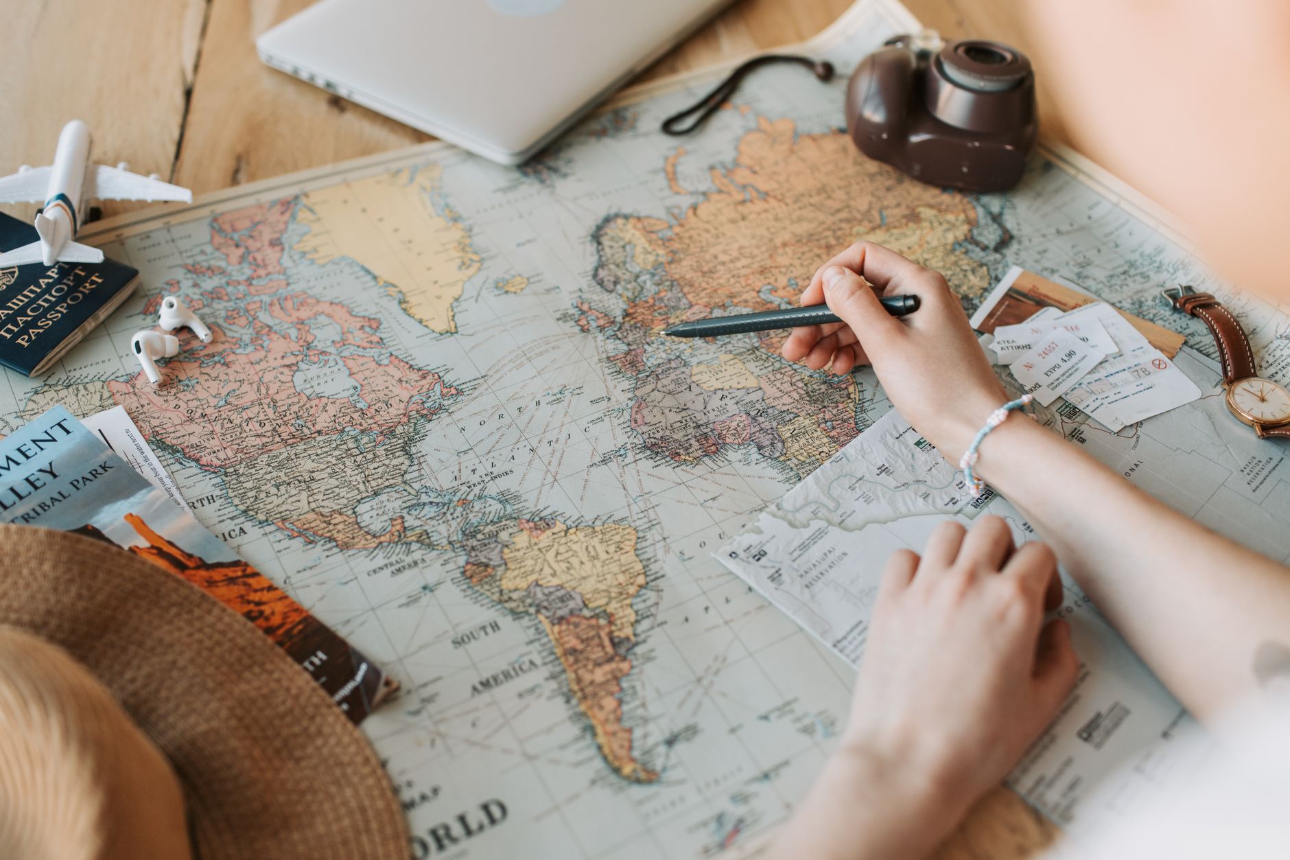 Reiseplanung über einer Weltkarte mit Pässen, Tickets und Kamera