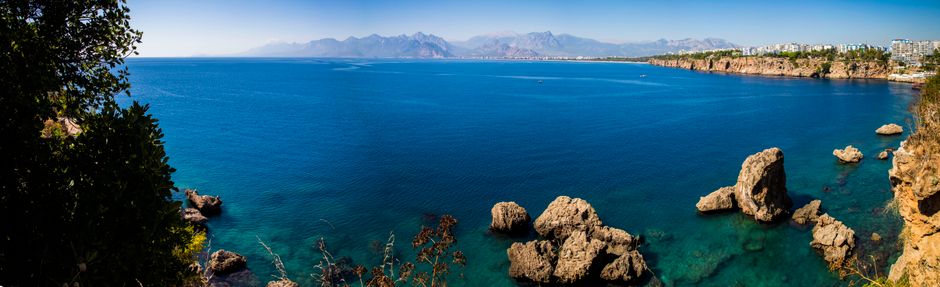 Türkisblaue Bucht mit Felsen und Bergkette am Horizont