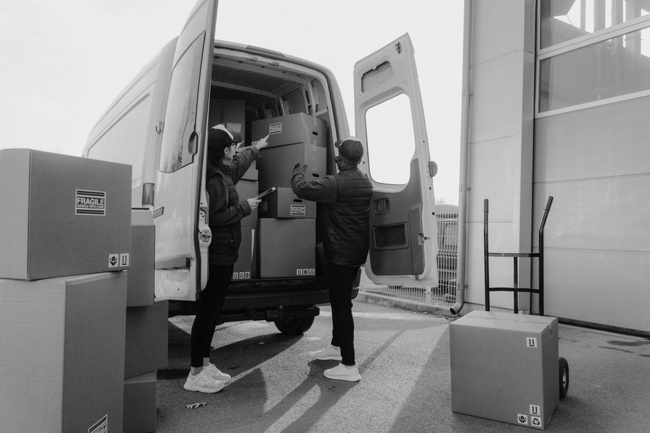 Team verlädt beschriftete Kartons in den Transporter