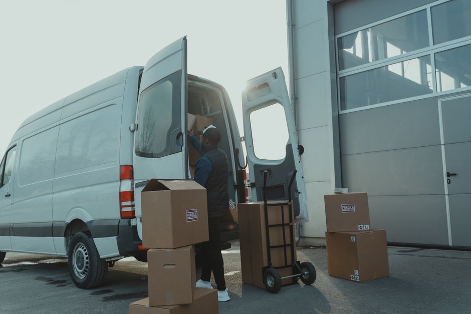 Möbelpacker mit Sackkarre am offenen Transporter
