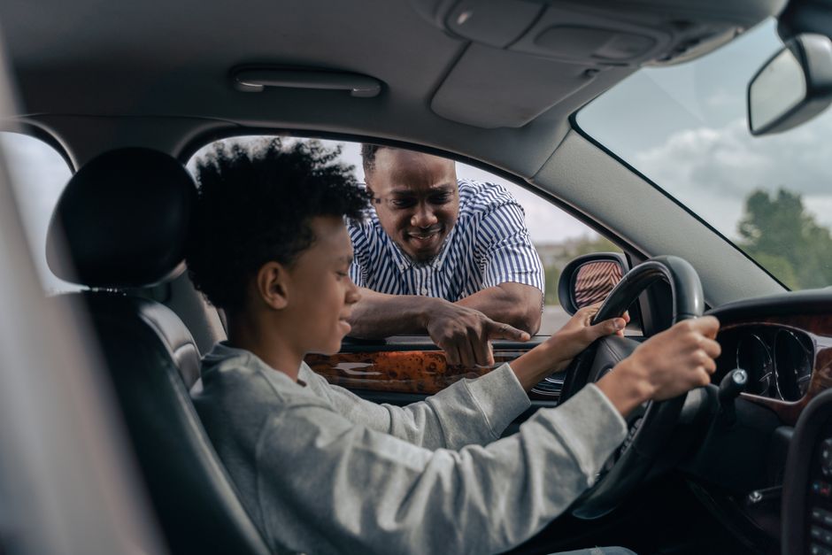 Fahrlehrer erklärt einer Schülerin etwas am Lenkrad