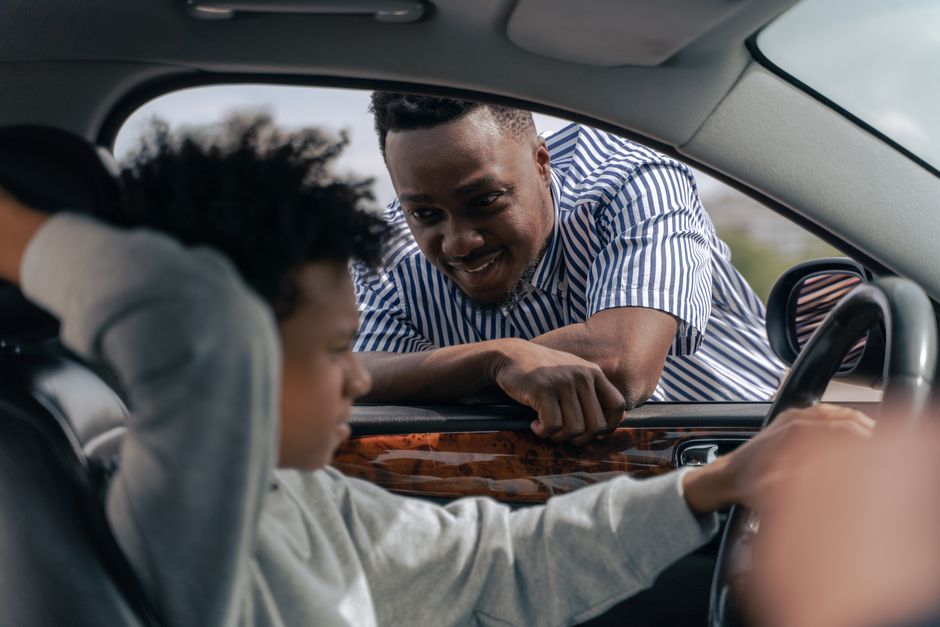 Fahrlehrer im Gespräch mit einem Fahrschüler am Seitenfenster
